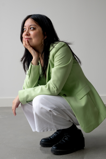 Amy in a fashionable outfit, crouched and smiling while into the distance. Photo credit Stellani Stampouli.
