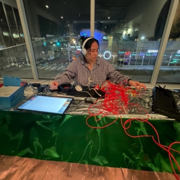 Portrait of Lillyanne Pham wearing headphones, working with tablets and mixers.